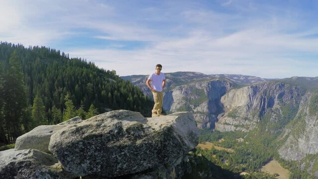 Tourist stands on rock near forest in Yosemite National Park
