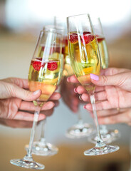 Hands with Champagne glasses with raspberry
