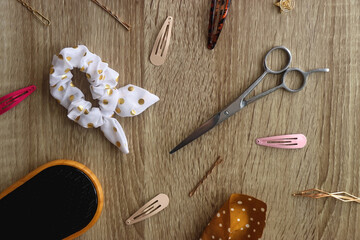 Wooden hairbrush, scissors and various headbands, hair clips and scrunchies on wooden background. Flat lay.
