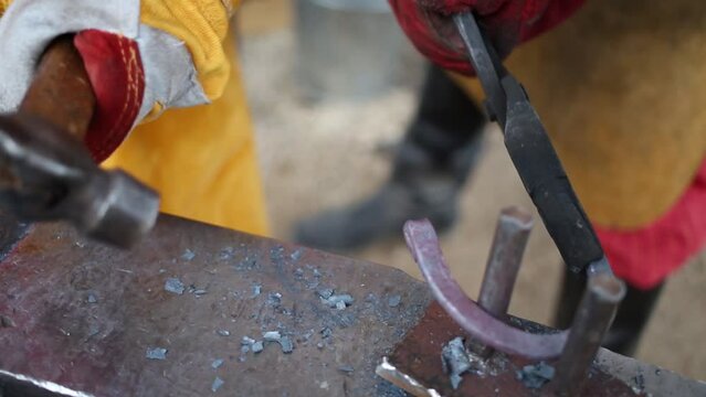 Hands of smith making horseshoe and other blacksmith helps him