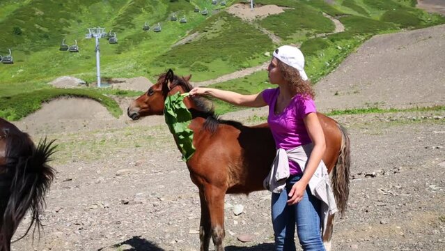 Beautiful woman fanning horse by leaf among mountains 