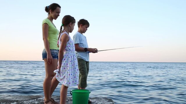 Mother and two children with fishing rod fishing in sea