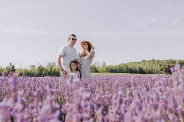 A happy family walks in a blooming purple lavender field. A mother holds her son in her arms, a...
