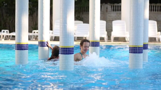 Smiling woman and girl swim in pool with Jacuzzi and rotunda