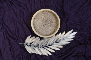 Ash and silver palm leaf on purple background. Ash Wednesday concept.
