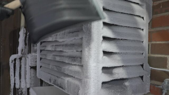 Air source heat pump outdoor unit covered with snow and frost due to condensation on a frosty winter day in Finland. Home heating in winter in the Nordic countries