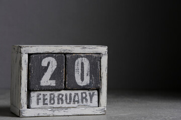 February 20 on wooden calendar, on dark gray background.