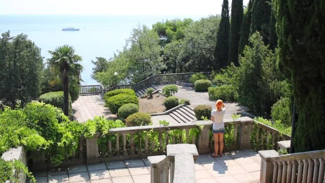 Woman on staircase looks at ship in tropical garden