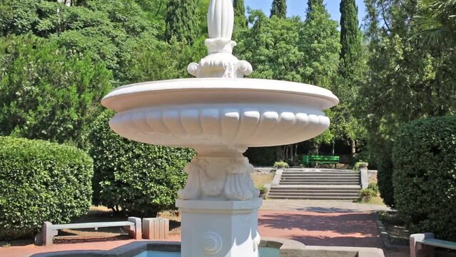 Old white fountain in tropical garden at summer day