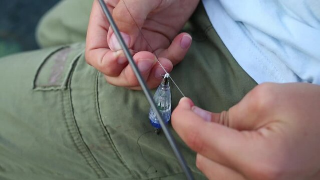 Hands of boy preparing bobber for fishing. Close-up view