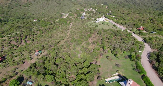 Aerial view of houses in the small town of Merlo, San Luis, Argentina. the drone flies over the houses and valleys and ends up in the mountains. the sky is clear on a beautiful day.