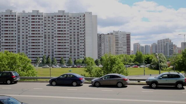 Cityscape with highrise buildings, blue sky and cars along road.