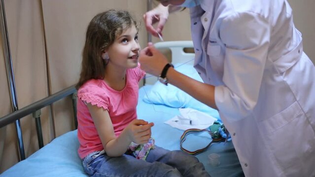 Female doctor fixes contacts of electroencephalograph at girl ears