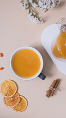 Cup and teapot of sea buckthorn tea and macaroon flat lay, top view. Cozy autumn winter time
