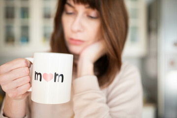 Caucasian woman, tired or thoughtful, holding a mother's  day cup of coffee. charge of parenting concept.
