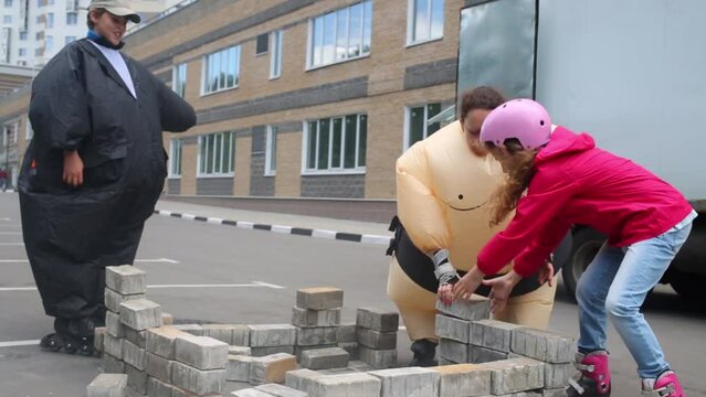 Woman and boy in inflatable costumes and girl on roller skates