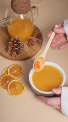 Female hands in a sweater hold a cup of sea buckthorn tea. Cozy autumn winter time