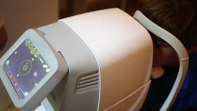 Boy looks in ocular of noncontact pneumotonometer 