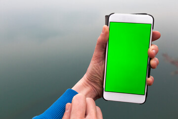 Woman Hands Checking Smart Phone With Green Screen on Water Surface of a River Background