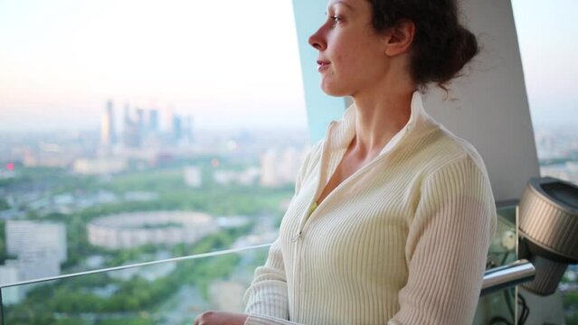 Beautiful woman looks into big window in high building