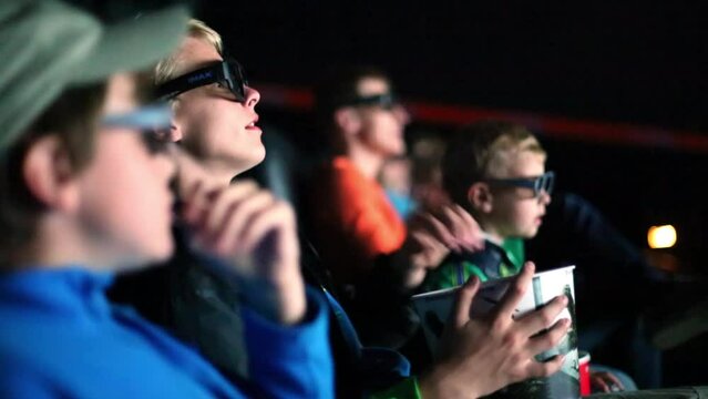 Three boys and theirs father watch a movie in 3D glasses 