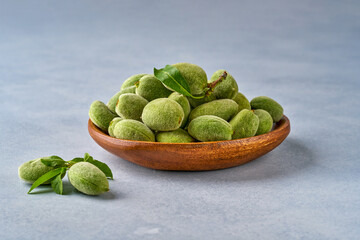 Fresh, unripe green almonds and green own leaves. Closeup