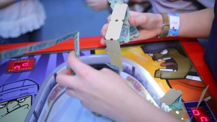 Boy gathers tickets from gaming table at amusement playground.
