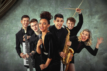 Fototapeta na wymiar Cheerful international music group on a gray wall background, a group of musicians posing on camera in the hands of various instruments, guitars, saxophone. Copy space.