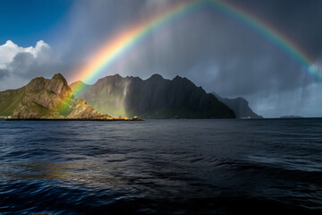 rainbow over the ocean with mountains in the background