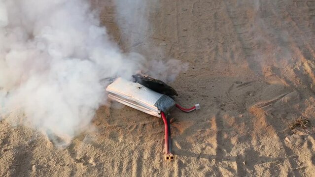 Burning lithium-polymer battery on sand outdoor with smoke