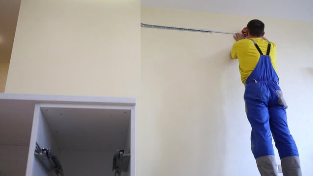 A worker measures the distance and makes a mark on the wall