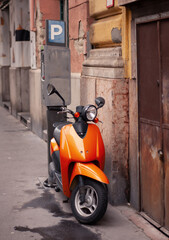 an orange moped stands on the street