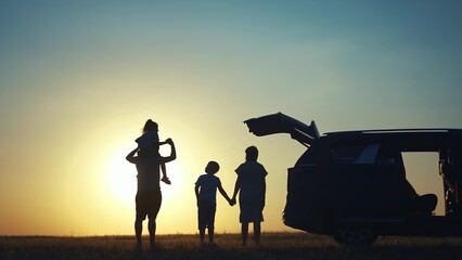 family traveling by car. family watching the sunset silhouette next to the car in the park. happy...
