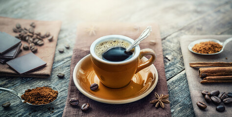 A cup of aromatic black coffee, a coffee maker, coffee beans of different varieties on the table....