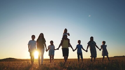 big family. huge community family holding hands walking in the park at sunset. happy family kid...