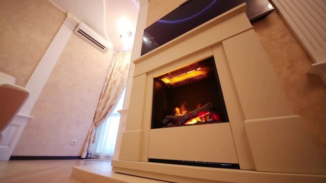 Under view of sofa and fireplace with burning logs in apartment