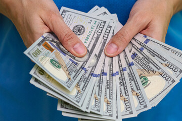 Close up view of hand holding dollar banknotes.