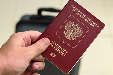 Closeup view of russian passport and grey suitcase.