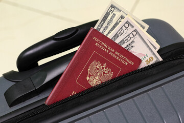 Closeup view of russian passport with US dollar banknotes and suitcase.