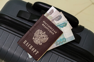 Closeup view of russian passport with russian ruble banknotes and suitcase.