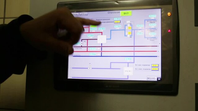 Touch screen on wall and male hand. Text on display: menu, heating, etc