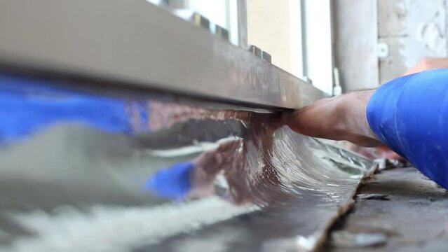 hands glue insulating foiled tape to window frame over windowsill