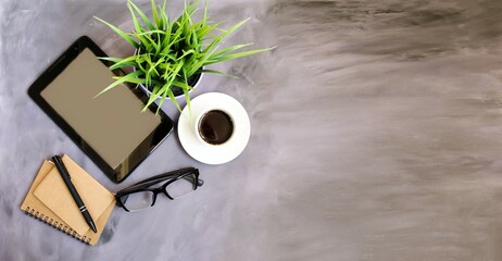 There is a tablet on the office table, a potted flower and a white cup of coffee next to the glasses.  Space for copy text, flat lay, top view, banner.  Concept training, online webinars, office work.