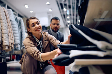Happy woman enjoying in buying clothing with her boyfriend in shopping mall.
