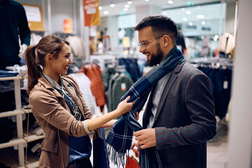 Young couple has fun while shopping in clothing store at mall.