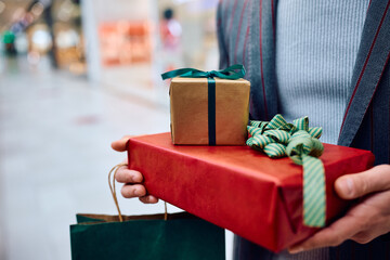 Close up of man with wrapped presents in shopping mall.