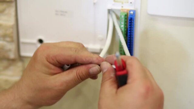 Male hands cut off unnecessary insulation from cable 
