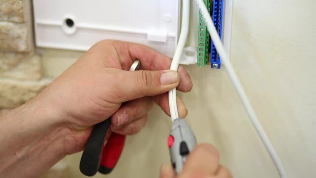 hands cut insulation along cable during preparing to installation