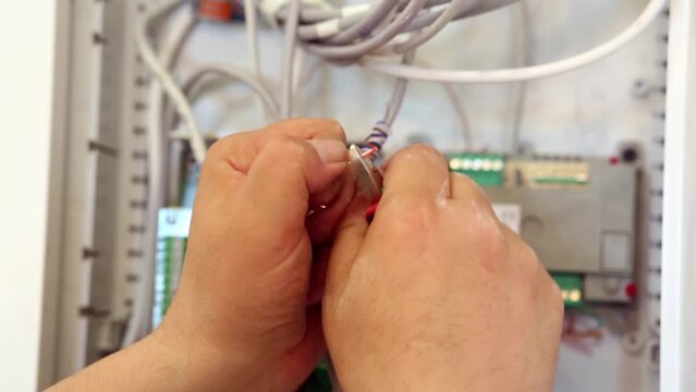 Worker hands strip wires from insulation before fix them 