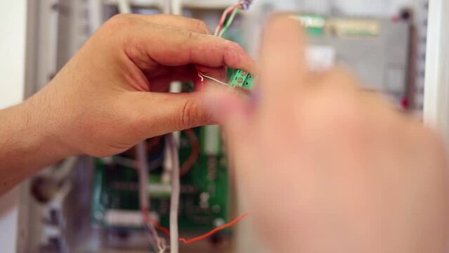 Worker hands fix twisted pair wires in terminal block.